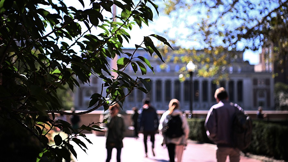 Students, faculty, and staff walking about on Columbia's Morningside campus with Butler Library in the background.