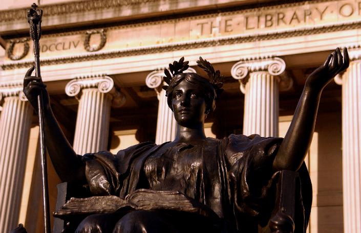 Upclose photo of the statue of Alma Mater with the emphasis of her eyes looking skyward with the pillars of Low Library behind the statue