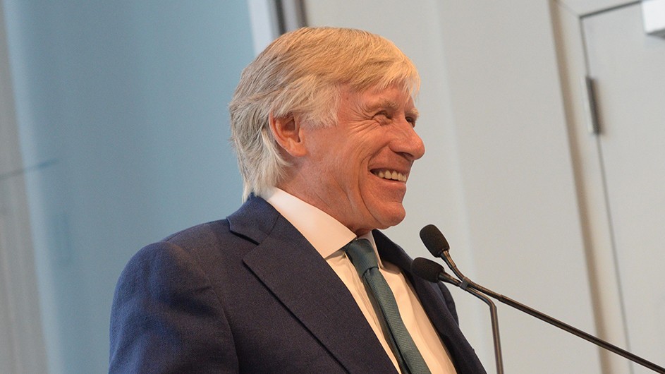 Eileen Barroso President Bollinger, a man in a suit and tie, at a podium, smiling