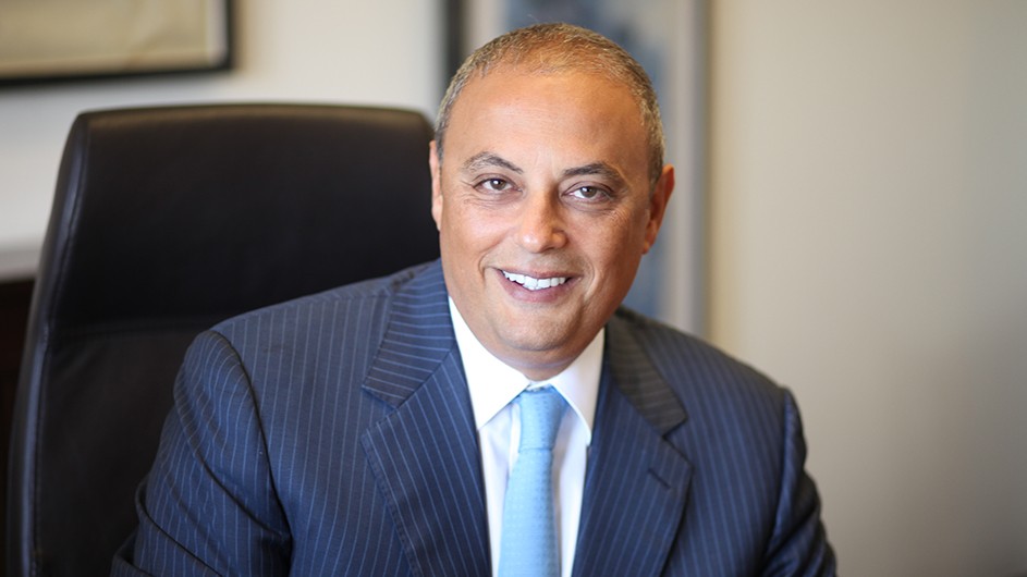Safwan Masri, a man with short hair in a dark blue suit and tie and a white shirt. 