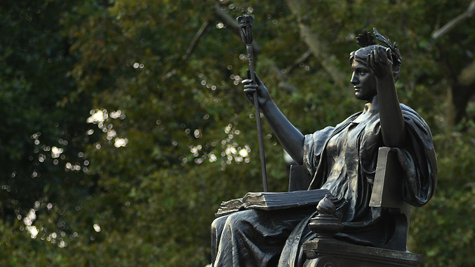 A bronze statue of Alma Mater, a woman with a laurel wreath in her hair, a scepter, and a classical robe. 
