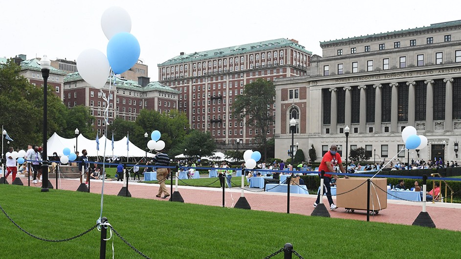 Columbia's Morningside campus, with a view of the buildings and balloons and people on College Walk, welcoming students back to campus. 