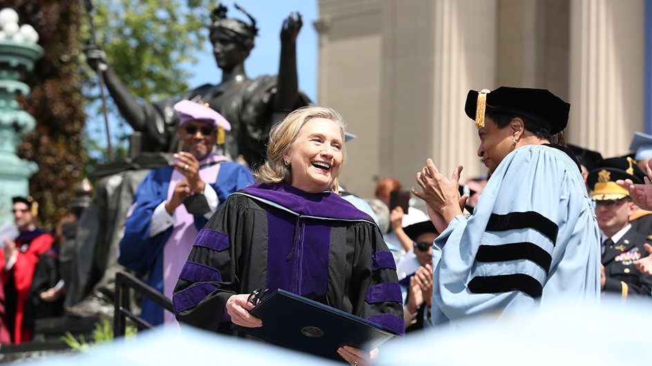Hillary Rodham Clinton, a woman with blond hair, smiling in a commencement robe. 