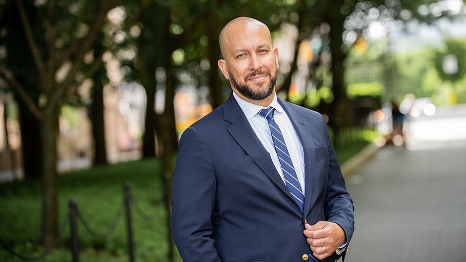 Josef Sorett, a man in a dark blue suit, standing outside, smiling.