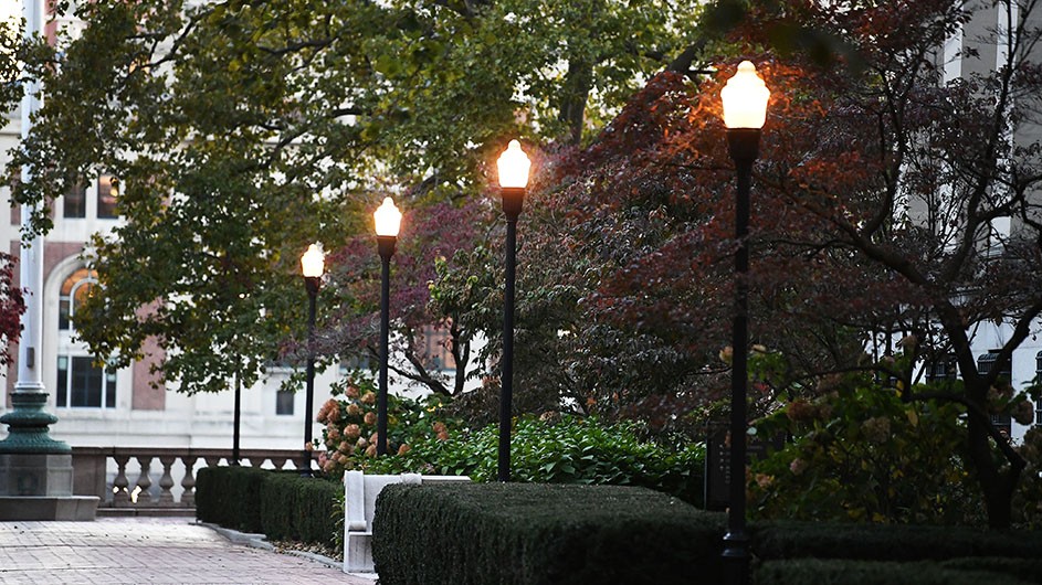 Street lamps are illuminated on Columbia's Morningside campus. 