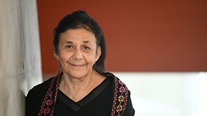 Wafaa El-Sadr, a woman with dark pulled back hair, in a black top with flowered trim
