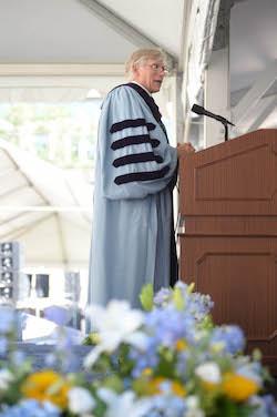 Lee Bollinger speaks at the podium at convocation in 2016 with flowers in foreground