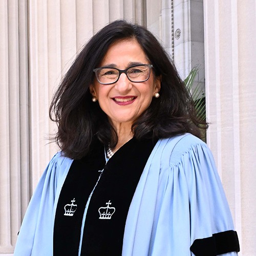 Minouche Shafik, a woman with dark hair and glasses in a light blue academic robe.