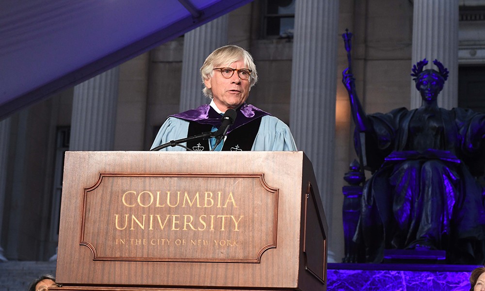 Photo of Lee Bollinger in front of Low steps and the statue of Alma Mater, addressing the crowd at Convocation