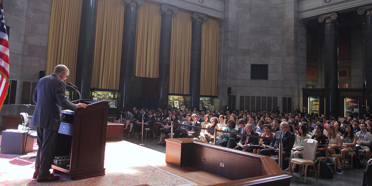 Photo of Lee Bollinger at a podium in Low Library, addressing an audience
