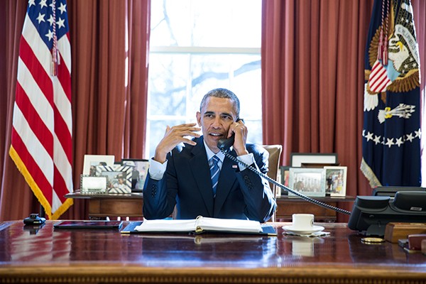 Photo of President Obama talking on the phone at his desk in the White House