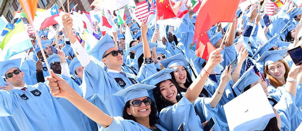 Photo of students at celebrating in the crowd at Commencement, waiving international flags. 