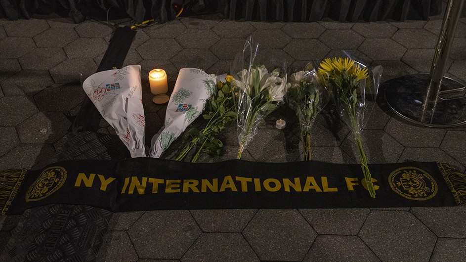 Lynn Saville Flowers and a candle above a black and yellow banner that says "NY International FC"
