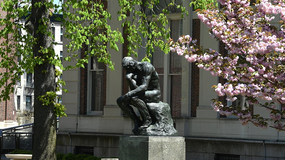 Sculpture of a male figure sitting down thinking, also known as "the thinker."