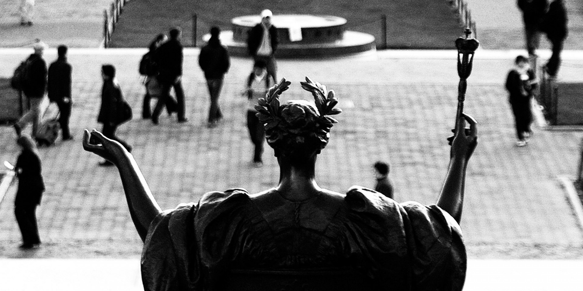 Alma Mater overlooking a group of people gathered, in black and white