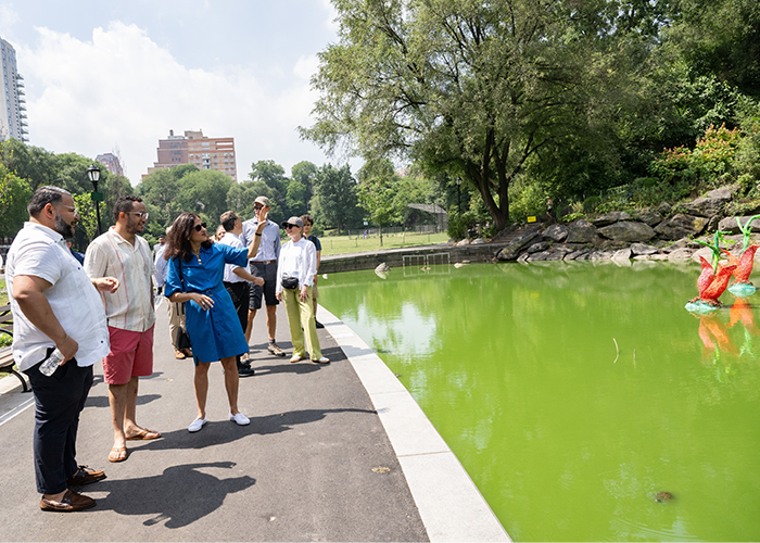A group of people gathered around a green pond.