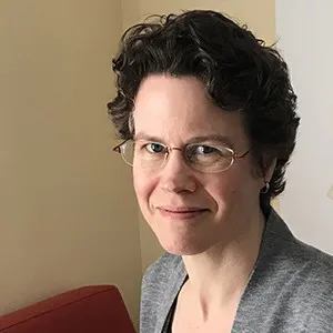 A woman with dark hair and glasses.