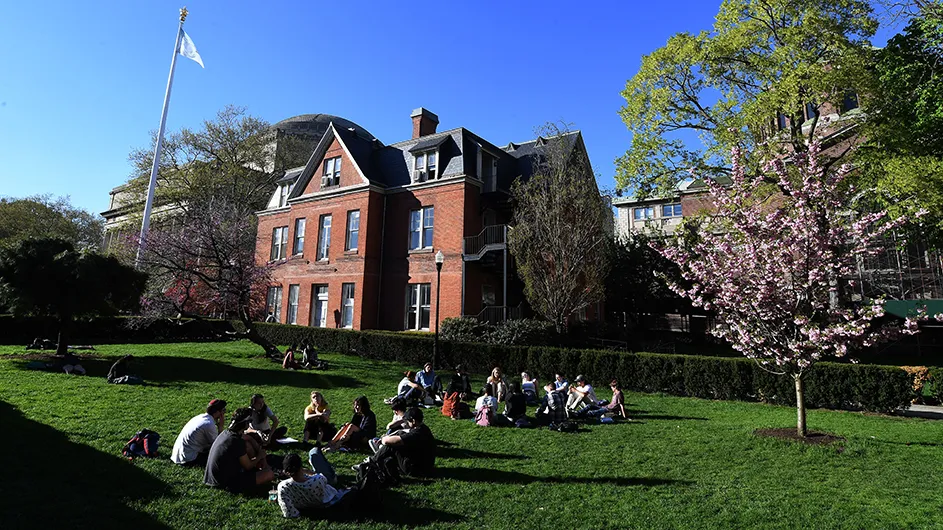 Groups of student gathered on Columbia's campus having conversations outside on the grass. 