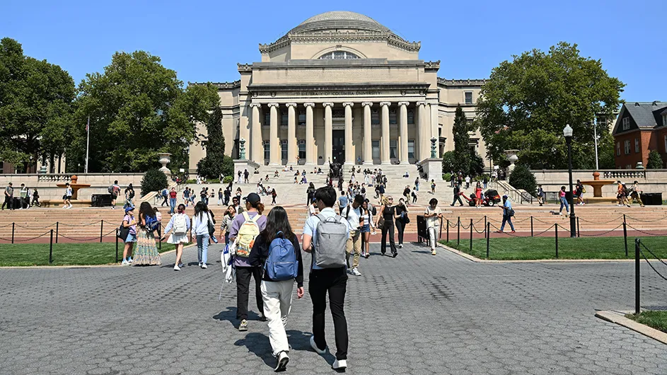 People walking around in front of Low Library, a classical building on Columbia's Morningside campus. 