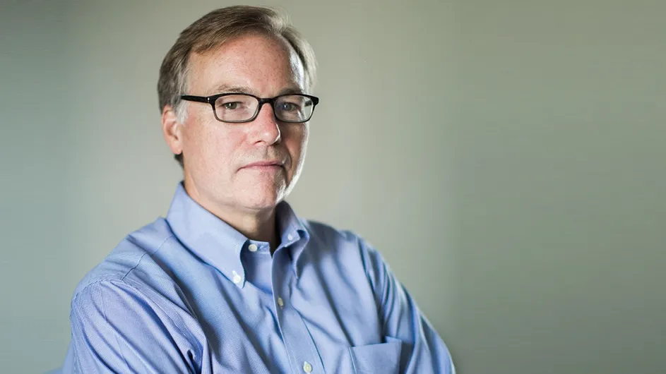 Headshot of a man with short hair and glasses, in a light blue shirt. 