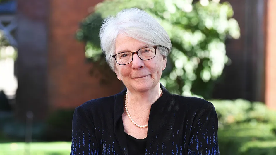 Jane Booth, a woman with short, white hair and glasses, standing outside.
