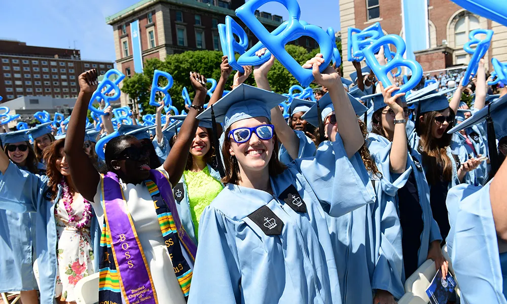Photo of students celebrating Commencement, waiving "b" shaped balloons in the air.