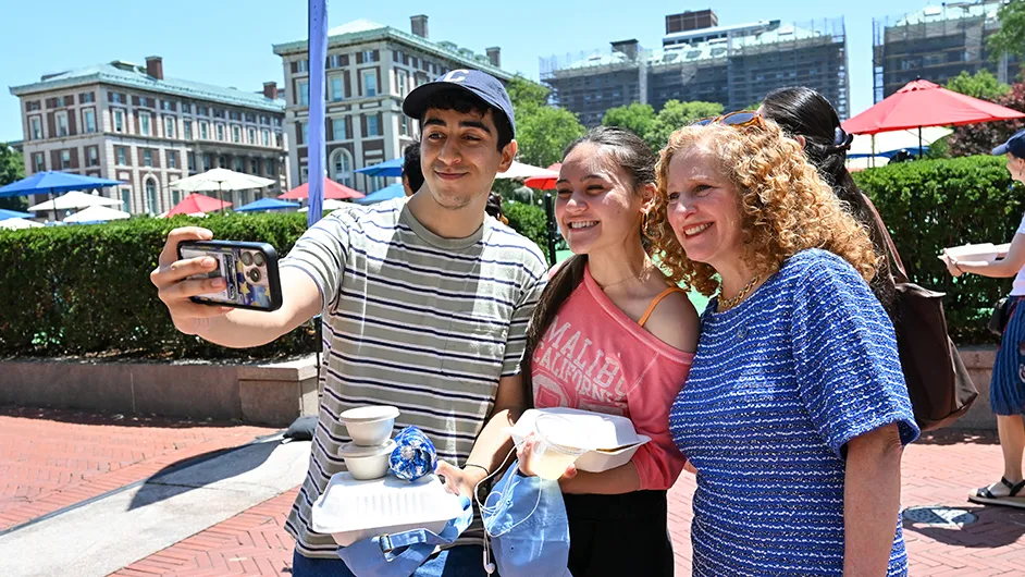 Three people standing outside taking a photo. 