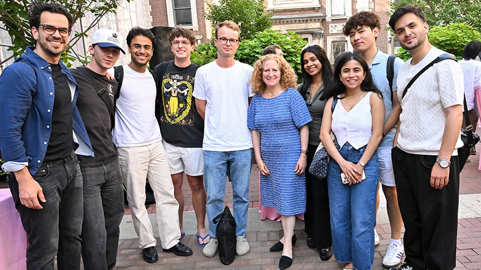 A group of people standing around outside, smiling. 