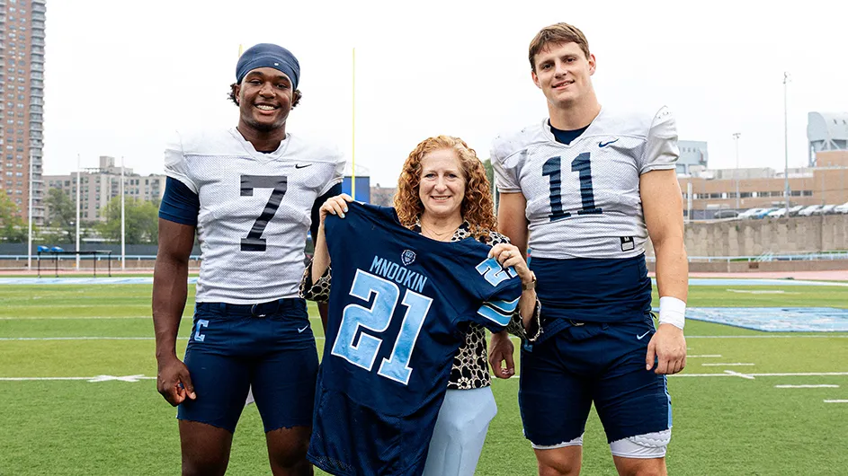 Two football players and one woman, all with jerseys. 