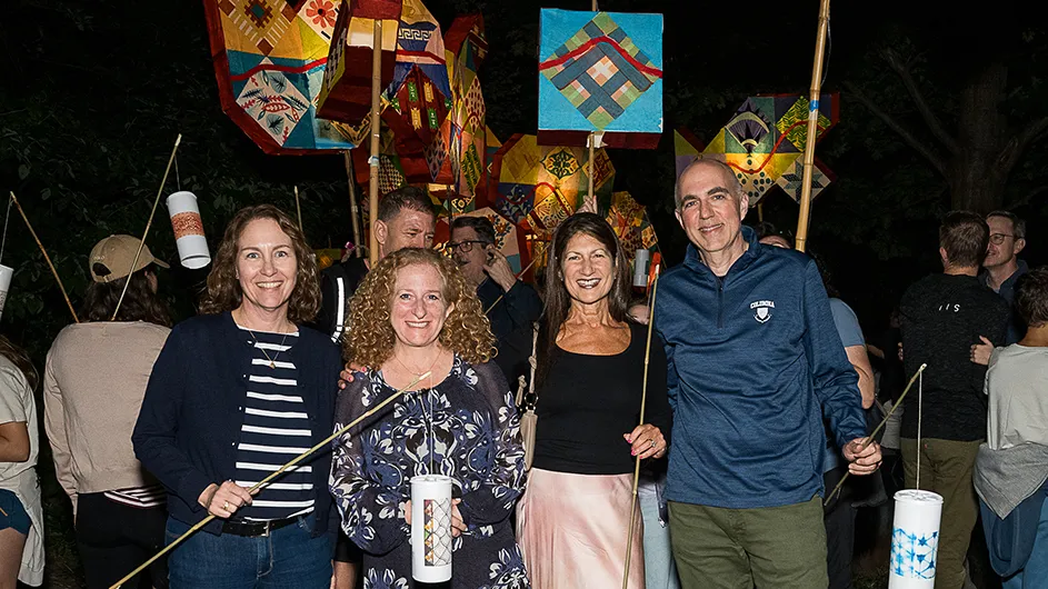 Four people standing against the backdrop of colorful lighted art creations. 