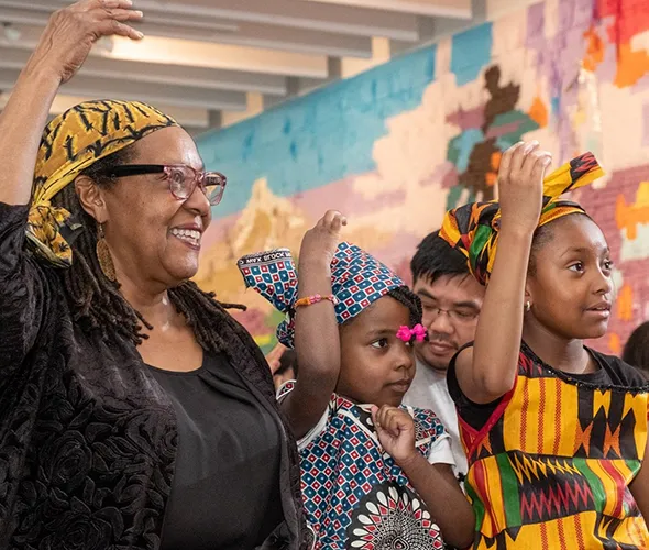 One woman and two children standing with one arm over their heads
